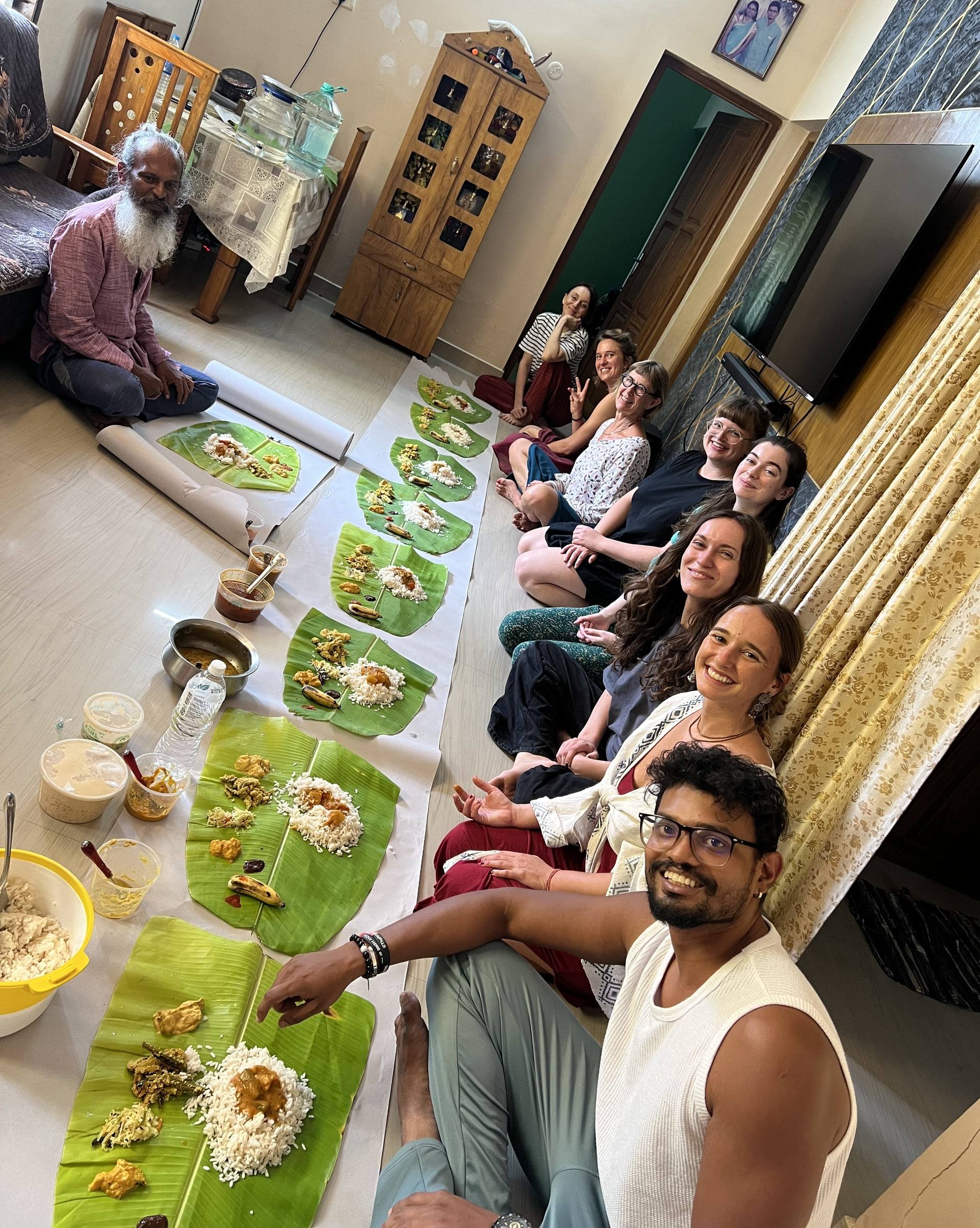 Students sitting on the floor for a vegetarian Kerala meal served on banana leaves